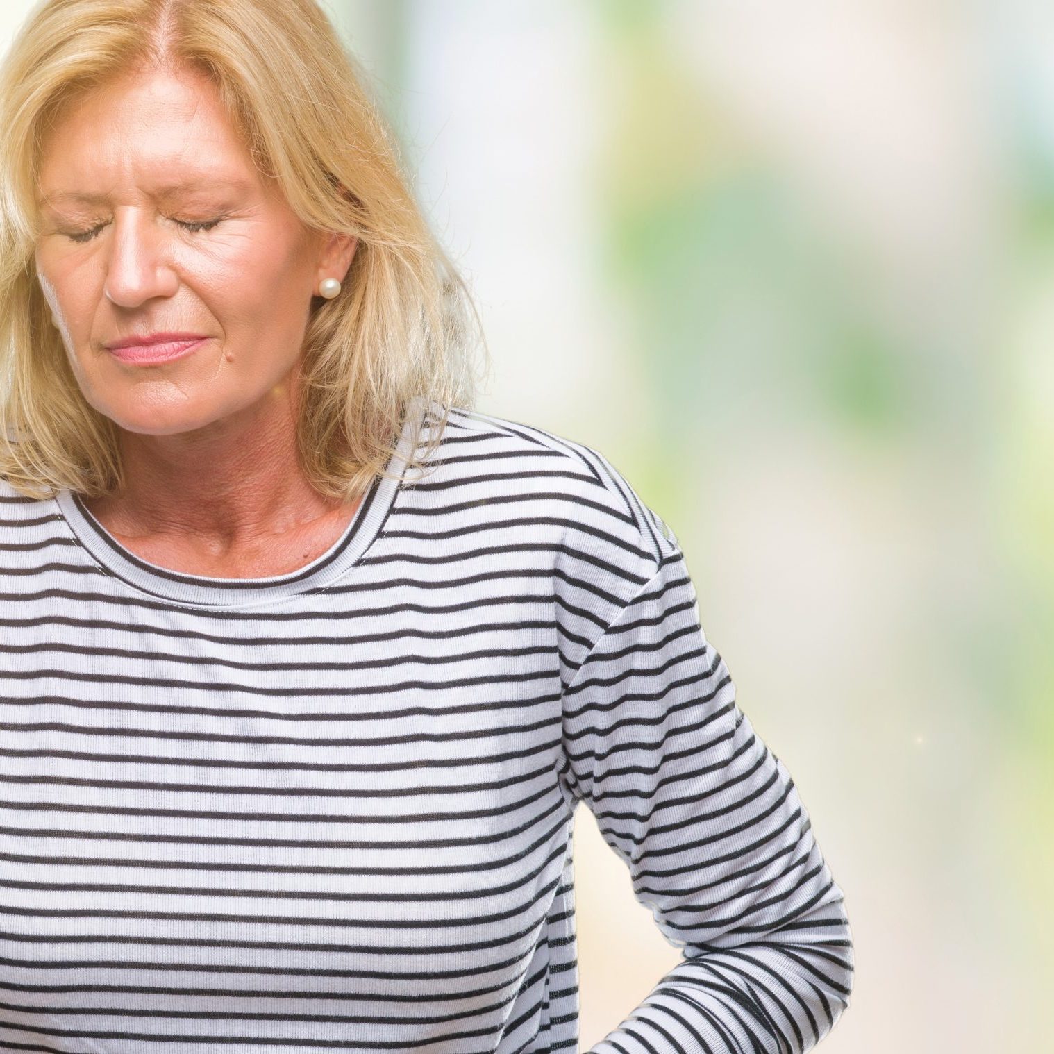 Middle age blonde woman over isolated background with hand on stomach because indigestion, painful illness feeling unwell. Ache concept.