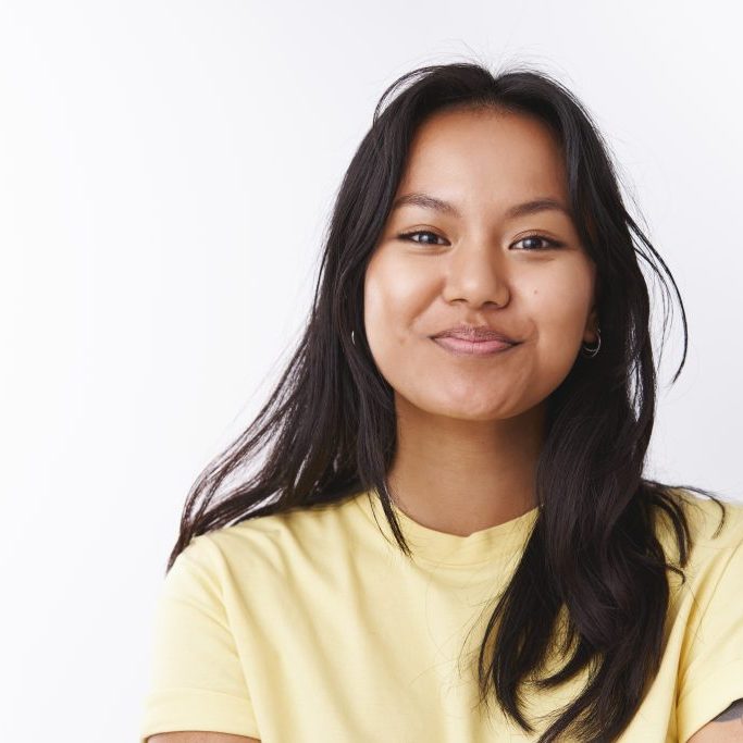 Close-up shot of amused enthusiastic good-looking malaysian woman with facial scars smiling feeling positive and optimistic grinning from happiness and good attitude over white background.
